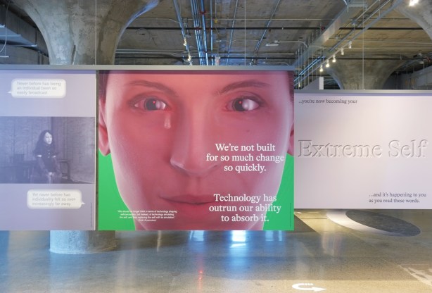 large panels hanging in an art gallery, MOCA, three panels. In the miiddle is a large picture of a woman's face with a single tear. Also some words. On the right is Too stupid to fail. On the left 