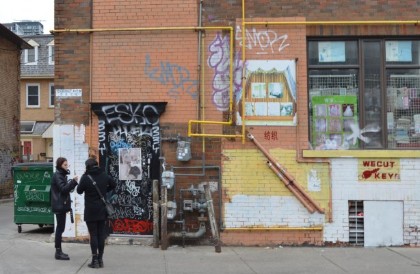 two women standing on a sidewalk, talking to each other,