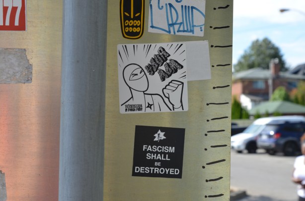 stickers on a pole, an urban ninja squadron and one that says fascism shall be destroyed