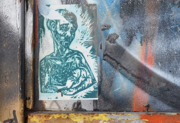 paste up in window of a man with depressed look on face, from waist up, holding a baby in his arms, in green tones