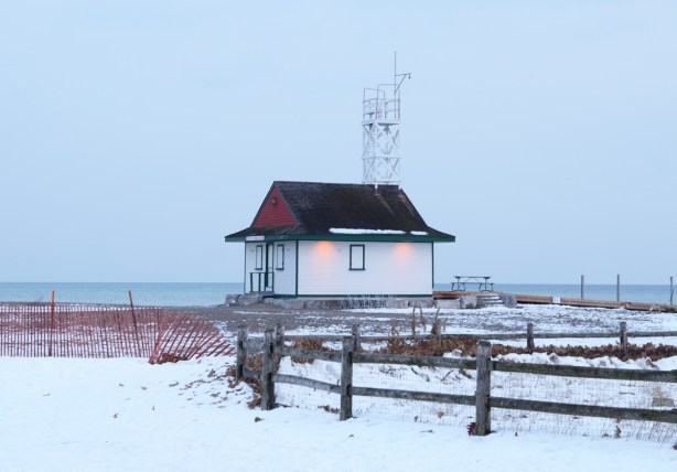 Leuty lifeguard station in late afternoon, snow fence, some snow on the ground, lights on, 