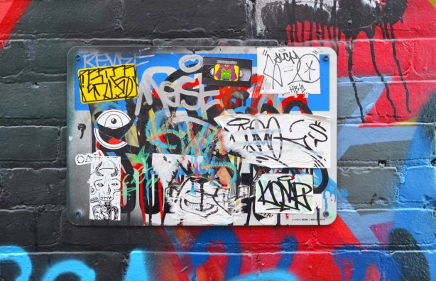 many stickers on a metal sign on a wall covered in street art.