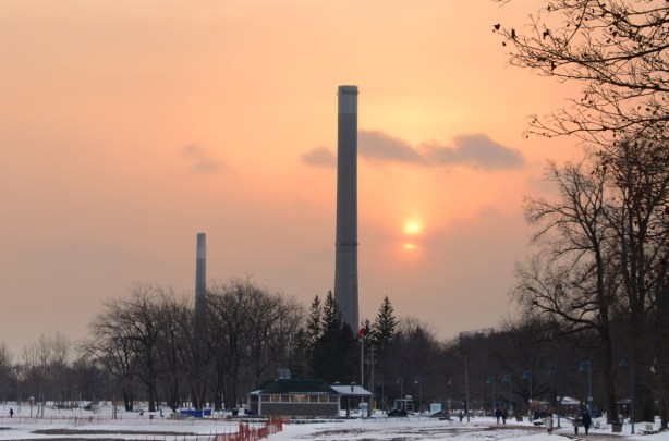 looking towards downtown Toronto from the boardwalk at Woodbine beach, sunset, orange colour with small clouds, some snow on the ground