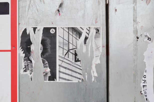 two posters that were glued to construction hoardings but that have been largely torn off 