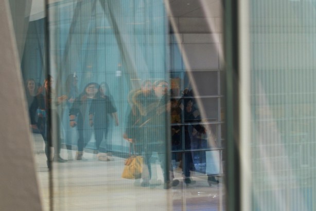 reflections of people walking in glass walled elevated walkway om downtown Toronto 