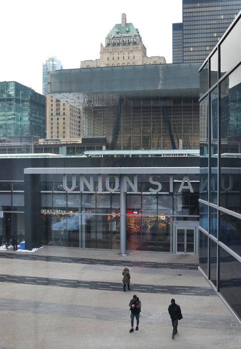 Union Station entrance, a couple of people walking in front, Royal York hotel in the background, taken from elevated walkway beside Scotiabank arena 