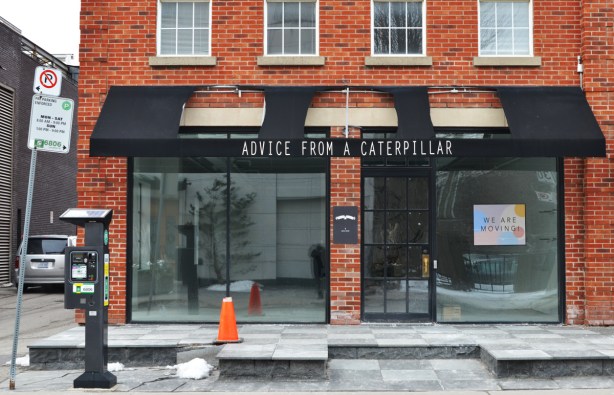 an empty storefront in a red brick building, black awning in front, words on awning say Advice from a caterpillar 