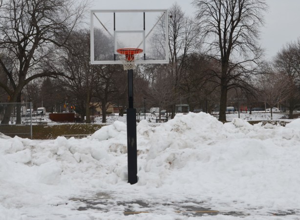 a basketball hoop on a metal pole in the snow in the park 