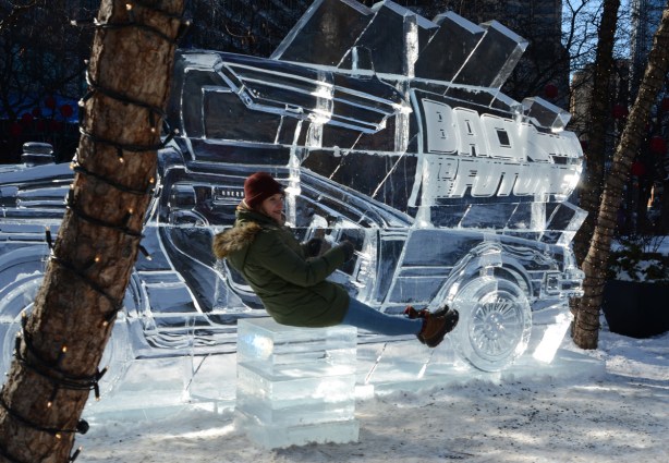 a woman posing with a large ice sculpture of a De Lorean car