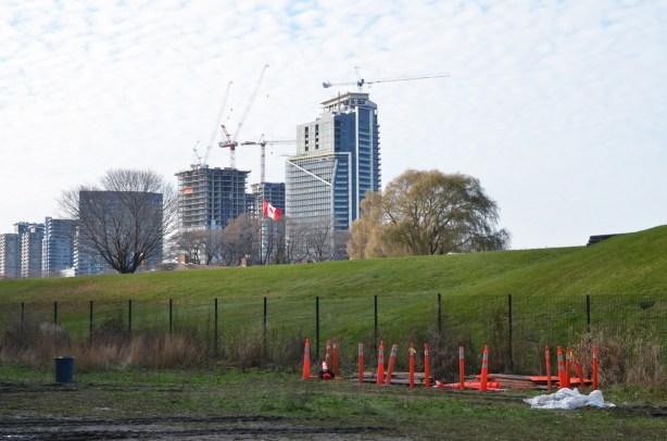 edge of the grounds of fort york, green grass on hill, with new high risse condos in the distance