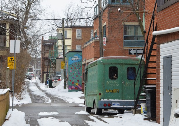 old green Chevrolet delivry van parked in a snowy alley, also part of a mural with hearts on it, alley scene