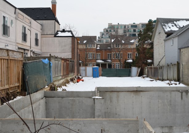 snow covered vacant lot with a concrete hole in the foreground, basement for a new house 