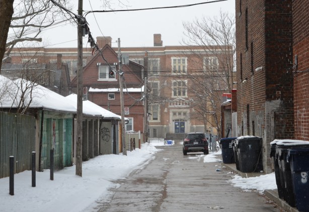 looking down a lane that runs parallel to St. Clair West, with Oakwood Collegiate in the background.