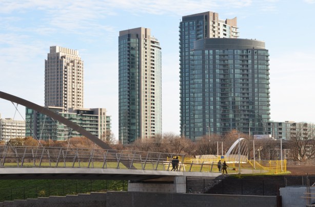 people walking across the Garrison Crossing bridge with high rise condos behind them 