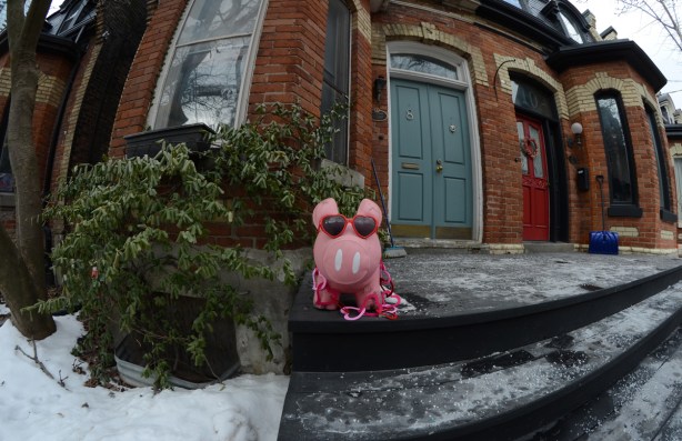 a pink plastic pig on a porch, wearing heart shaped sunglasses and a necklace of heart shapes