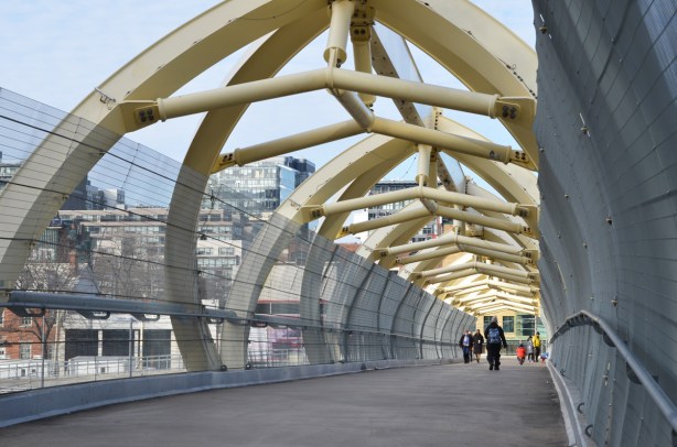 three people crossing the puente de luz, the yellow pedestrian bridge that crosses the railway tracks 