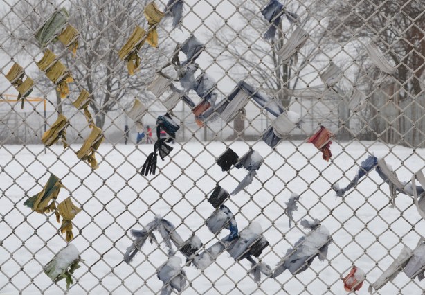 remnants of fabric or paper that has been wrapped around parts of a chainlink fence at a school yard