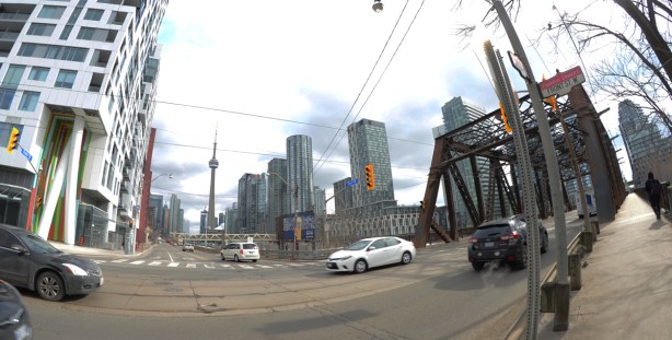 traffic at the intersection of Bathurst and Front. Brown metal bridge for Bathurst over the tracks, CN Tower and new condos in the background