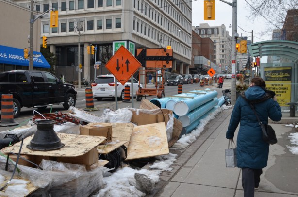 a woman walking on a sidewalk past a construction zone