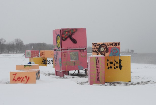 tagged and graffiti covered pink and yellow boxes stacked on the beach, art installation by Centennial College students. 