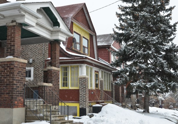 two storey barn style house, brick, with large pine tree in front yard