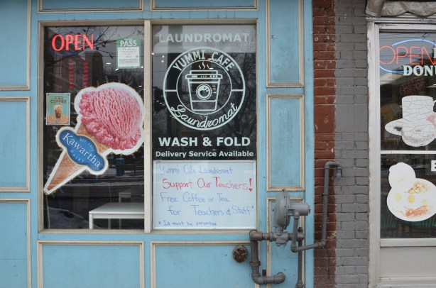 storefront, yummi cafe and laundromat, picture of pink ice cream cone as an ad for Kawartha Dairy, also a sign that says support your teachers, offering them free coffee