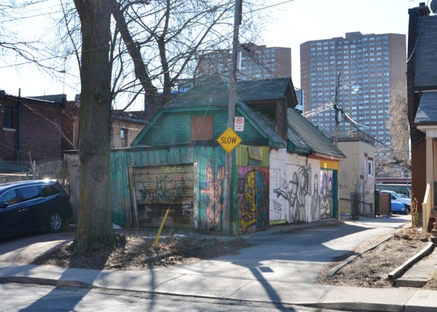 into the sun, long shadows, looking towards an alley with an old building covered with street art
