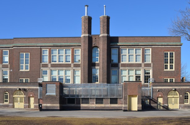 back of older brick public school, Bruce Public school with pair of chimneys and rows of windows, symmetrical. 