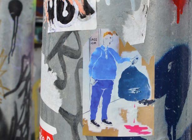daught calm sticker on a pole of a man in blue pants and sweatshirt holding up a leaking bag of garbage 