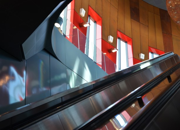 escalator and the wood wall beside it with windows with red frames, light coming in windows
