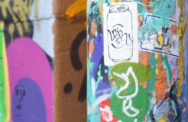 white soda can, pop can, draawing on a sticker, on a graffiti covered wall 