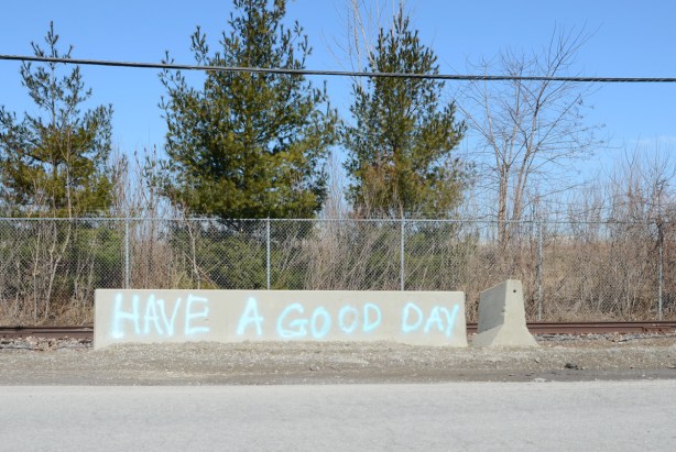 a concrete road barrier with blue spray paint words that say have a good day