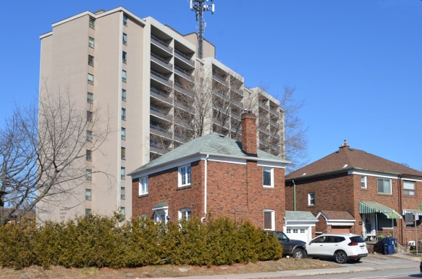 two brick houses in front of a tall apartment building 