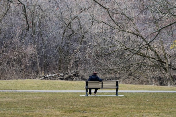 a man sitting on a bench in a park