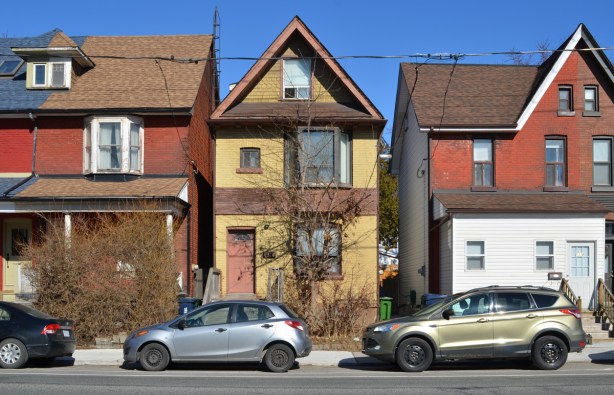 houses on a street with the one being an old narrow two storey house in yellowish brick