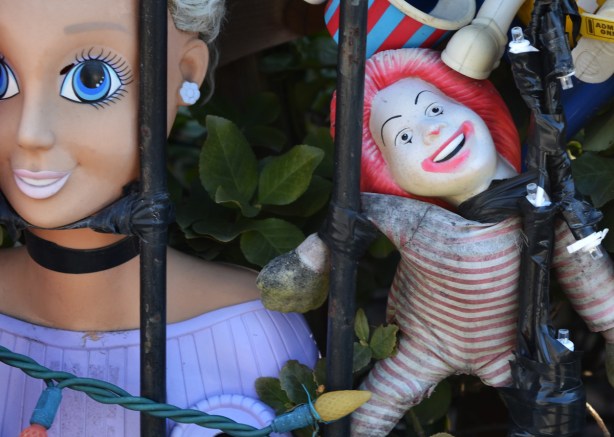close up of two of the dolls attached to the railing in front of house