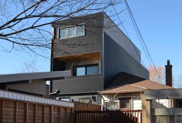 the back of a house, a semi divided house where one side is the original one storey while the other side has added two storeys and is taller than the surrounding houses, and it is narrow too 