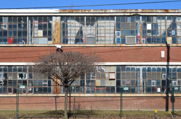 south wall of Parkhurst knitting mills, empty and abandoned, many glass panes cracked or broken, old curtains in the window