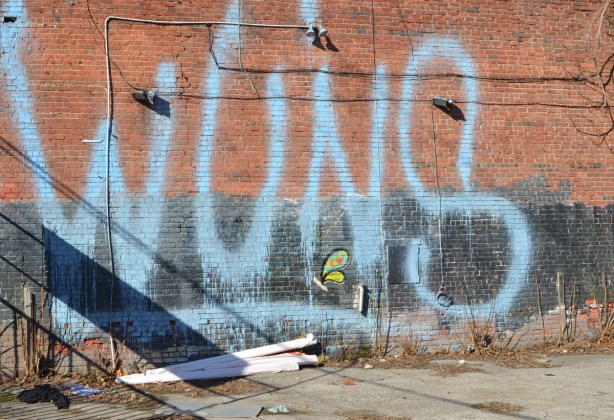 spray paint, large letters, wuns on a wall beside a vacant lot
