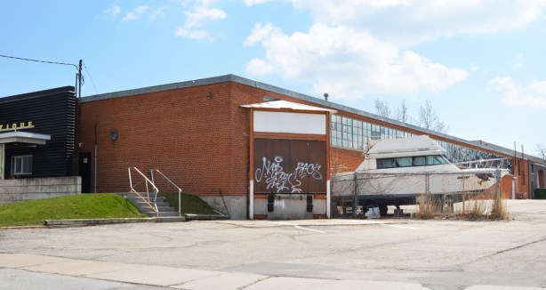 low rise brick light industrial building with an old boat parked beside it 
