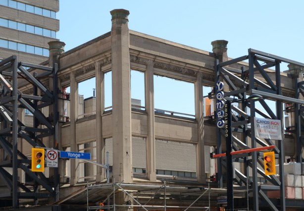 facade of a building on a corner being saved while rest of building is demolished 