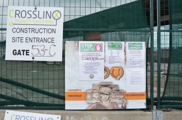 signs re covid-19 on a green fence around a construction site 