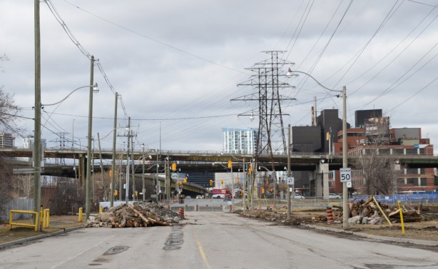 looking north on the closed portion of the Don Roadway, lumber pile in middle of road, large metal hydro poles, 