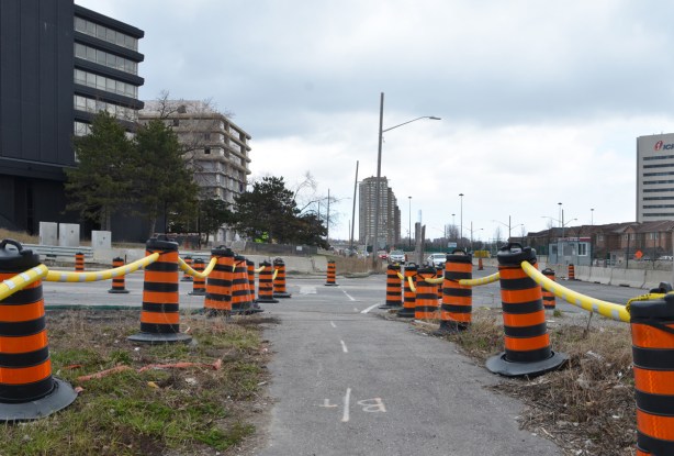 line of orange and black traffic cones on both sides of the sidewalk along Eglinton through Crosstown construction zone 