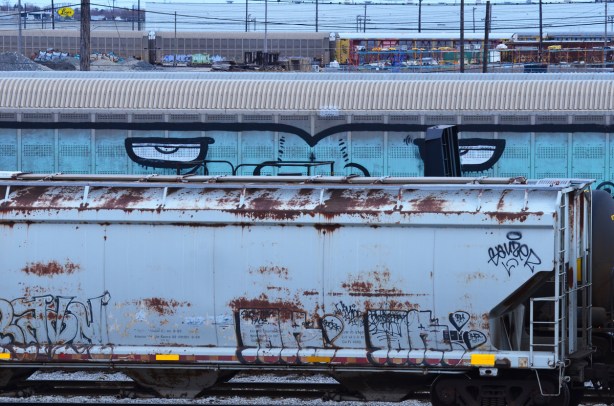 graffiti on the side of a train car - painted pale blue with two big eyes that seem to be looking at the viewer 