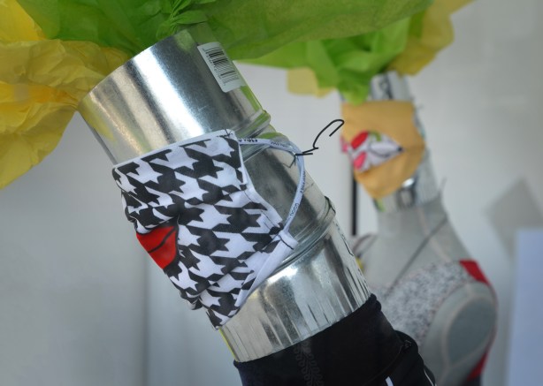 mannequins with metal stovepipe as neck and head, wearing covid face masks, one is black and white pattern with big red lips