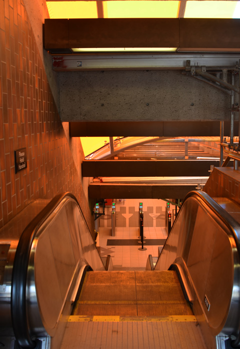 interior of Glencairn station, escalator going down, colour yellow from the glass roof that is being refurbished 
