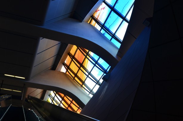 oval shape window at highway 407 subway station, painted in turquoise and oranges, escalator