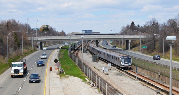 looking north on the Allen Expressway from the bridge over it at Glencairn, some traffic on the road, a subway track northbound on the tracks between the two sections of the Allen 