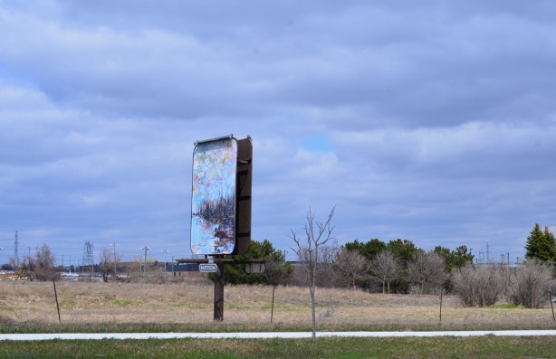 pattison billboard beside a street, on a vacant piece of land 
